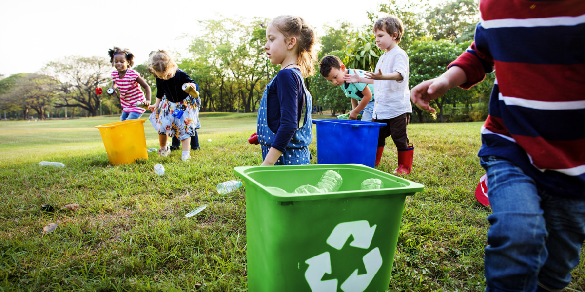 Volunteer kids take a trash to recycle bin