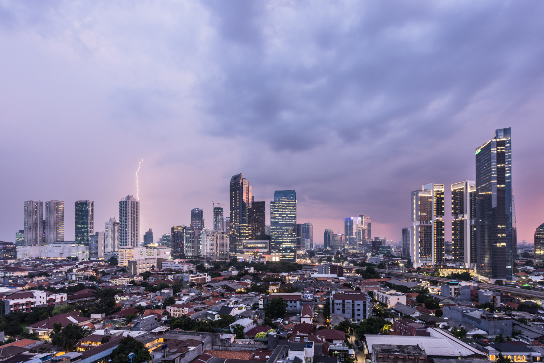 Aerial view of a sunset sky charged with storm clouds and a lightning over Jakarta business district in Indonesia capital city in Southeast Asia